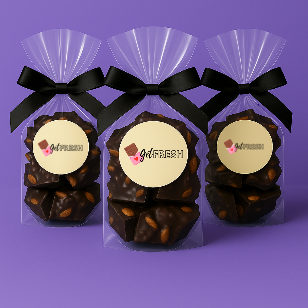 Triple-pack bundle of GetFresh Dark Chocolate Almond Bark in clear bags tied with black satin bows, arranged against a pastel purple background—perfect for gift sets or bulk buys.